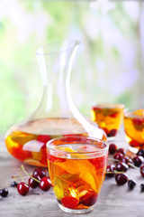 Punch with berries in glassware on wooden table on light blurred background