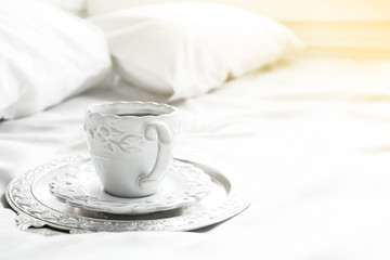 Morning cup of coffee on comfortable bed in bedroom