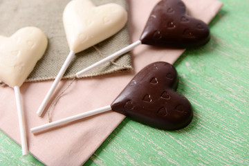 Chocolate heart shaped candies on sticks on sackcloth, closeup