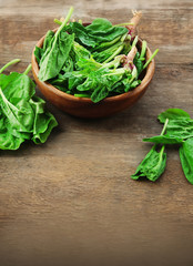 Bowl of fresh spinach leaves on wooden background