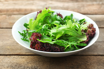 Bowl of mixed green salad on wooden background
