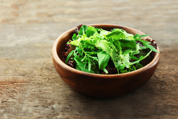 Bowl of mixed green salad on wooden background