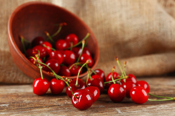Fototapeta na wymiar Fresh cherries in bowl on wooden table with sackcloth, closeup