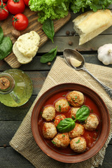 Meat balls with tomato sauce, wooden spoon on wooden background