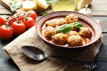 Meat balls with tomato sauce, wooden spoon on wooden background