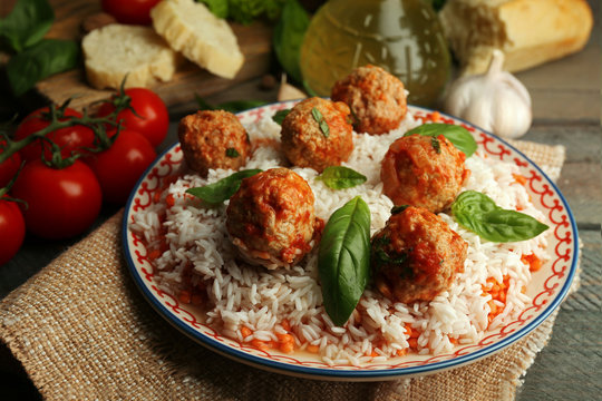 Meat balls in tomato sauce with boiled rice and lentil, wooden spoon on wooden background