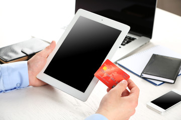 Man holding credit card and tablet on workplace background