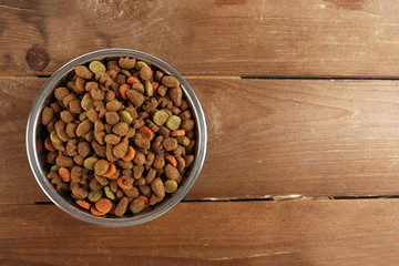 Dog food in bowl on wooden table