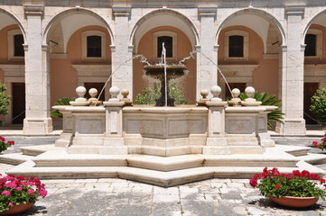Fototapeta premium Stone fontana against the building with arcades in the Monastery of Monte Cassino