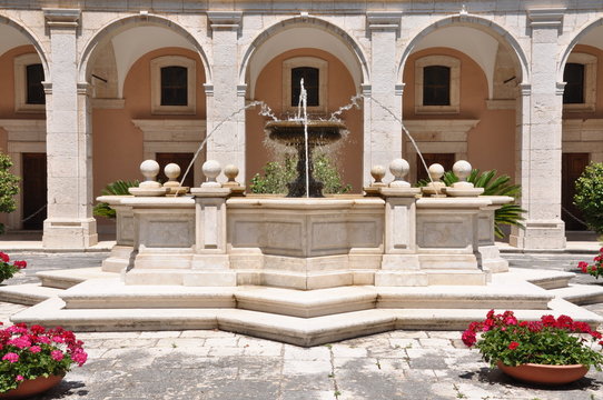 Stone fontana against the building with arcades in the Monastery of Monte Cassino