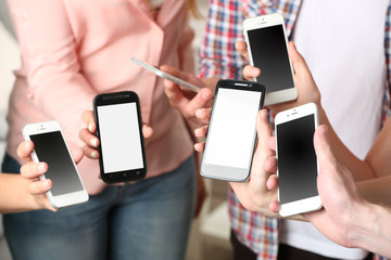 Many hands holding mobile phones close up