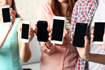 Many hands holding mobile phones close up