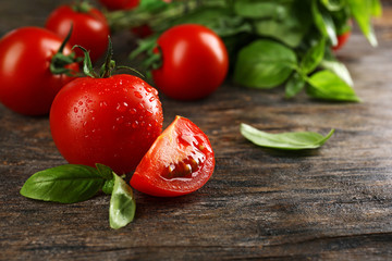 Cherry tomatoes with basil on wooden table close up