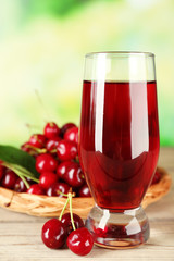 Glass of fresh juice with cherries on bright background