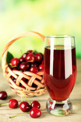 Glass of fresh juice with cherries on bright background