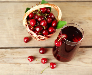 Glass of fresh juice with cherries on wooden table close up