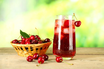 Glass of fresh juice with cherries on bright background