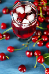 Glass of fresh juice with cherries on wooden table close up