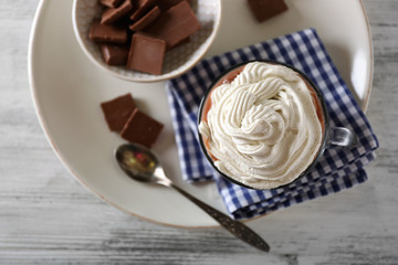 Cup of coffee with cream on color wooden background