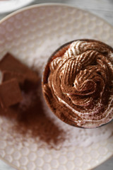 Cup of coffee with cream on color wooden background