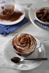 Cup of coffee with cream on color wooden background