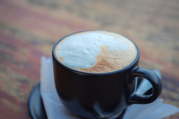 Coffee in black cup on wood table
