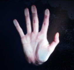 Female hand behind  wet glass, close-up