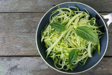 Grated zucchini and squash in pan on wooden table close up