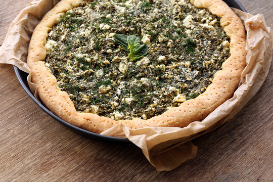 Open pie with spinach on table close up