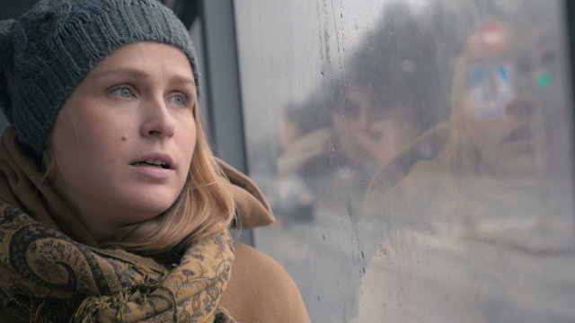 Young sad woman in the bus on a dull rainy day