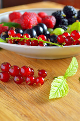 Assorted fresh garden berries on a  wooden background, close-up, raspberry,  black and red currant, gooseberry, blackberry.