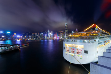 Obraz premium Illuminated Cruise ship and panoramic skyline of hong kong