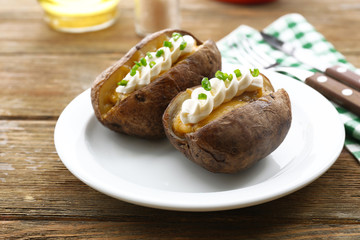 Baked potato mayonnaise and chives in white plate on wooden table, closeup