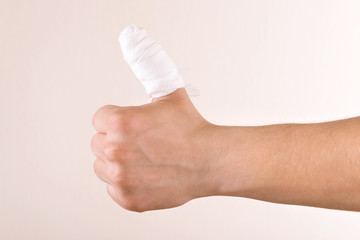 Injured bandaged finger on beige background