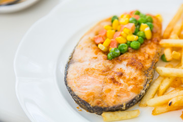 Grilled salmon steak meal served with salad and French fries