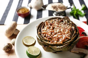 Vegetarian stuffed artichoke on plate, on table background