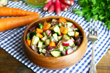 Wooden bowl of fresh vegetable salad on napkin, closeup