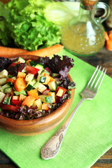 Wooden bowl of fresh vegetable salad on napkin, closeup