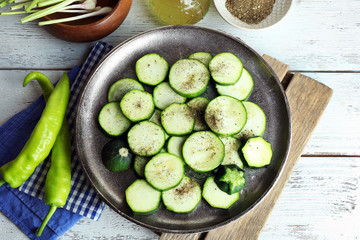 Sliced zucchini in metal tray on wooden table, top view
