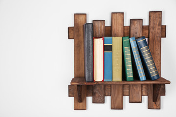 Wooden shelf with books on wall background