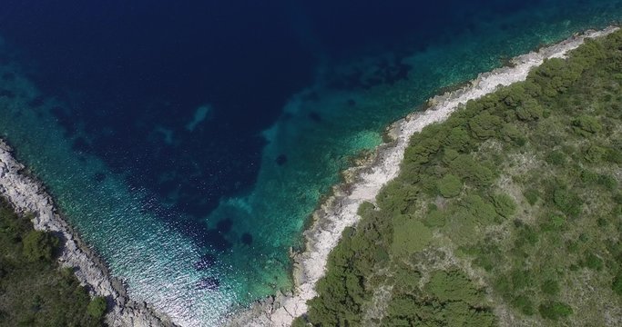 Escena aérea de isla rocosa en Croacia, costa dálmata. Detalle de la costa, barcos, catamarán, yates, veleros y texturas de vegetación, vista en planta. Cámara se mueve lentamente a través de la isla.