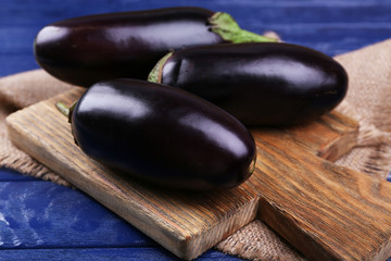 Fresh eggplant on cutting board on wooden table, closeup