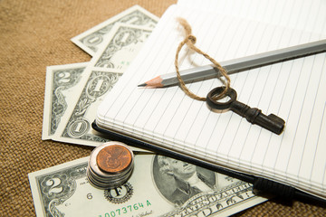Opened notebook, pencil, key and money on the old tissue