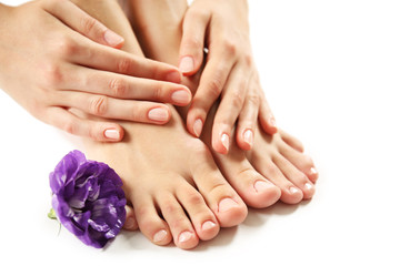 Female feet at spa pedicure procedure with flower isolated on white