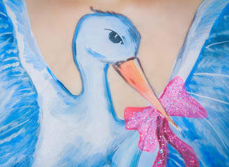 Pregnancy woman with body art of stork