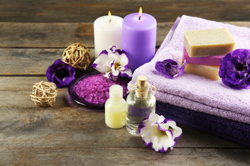 Obraz na płótnie Canvas Spa still life with towels, purple flowers and candlelight on wooden background