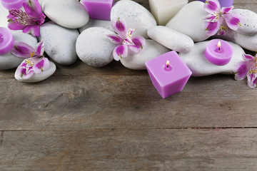 Spa still life with purple flowers, pebbles and candlelight on wooden background