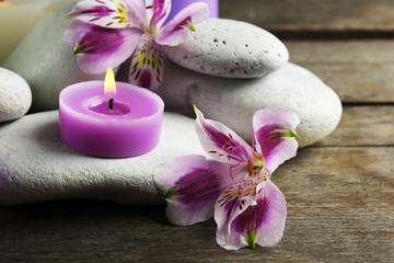 Fototapeta na wymiar Spa still life with purple flowers, pebbles and candlelight on wooden table, closeup