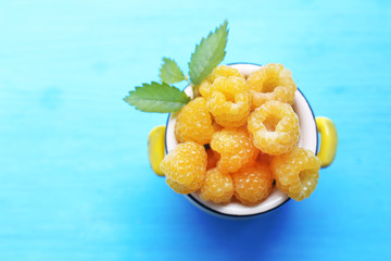 Yellow raspberries on turquoise table, top view