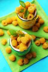 Yellow raspberries in cups on green napkins, closeup